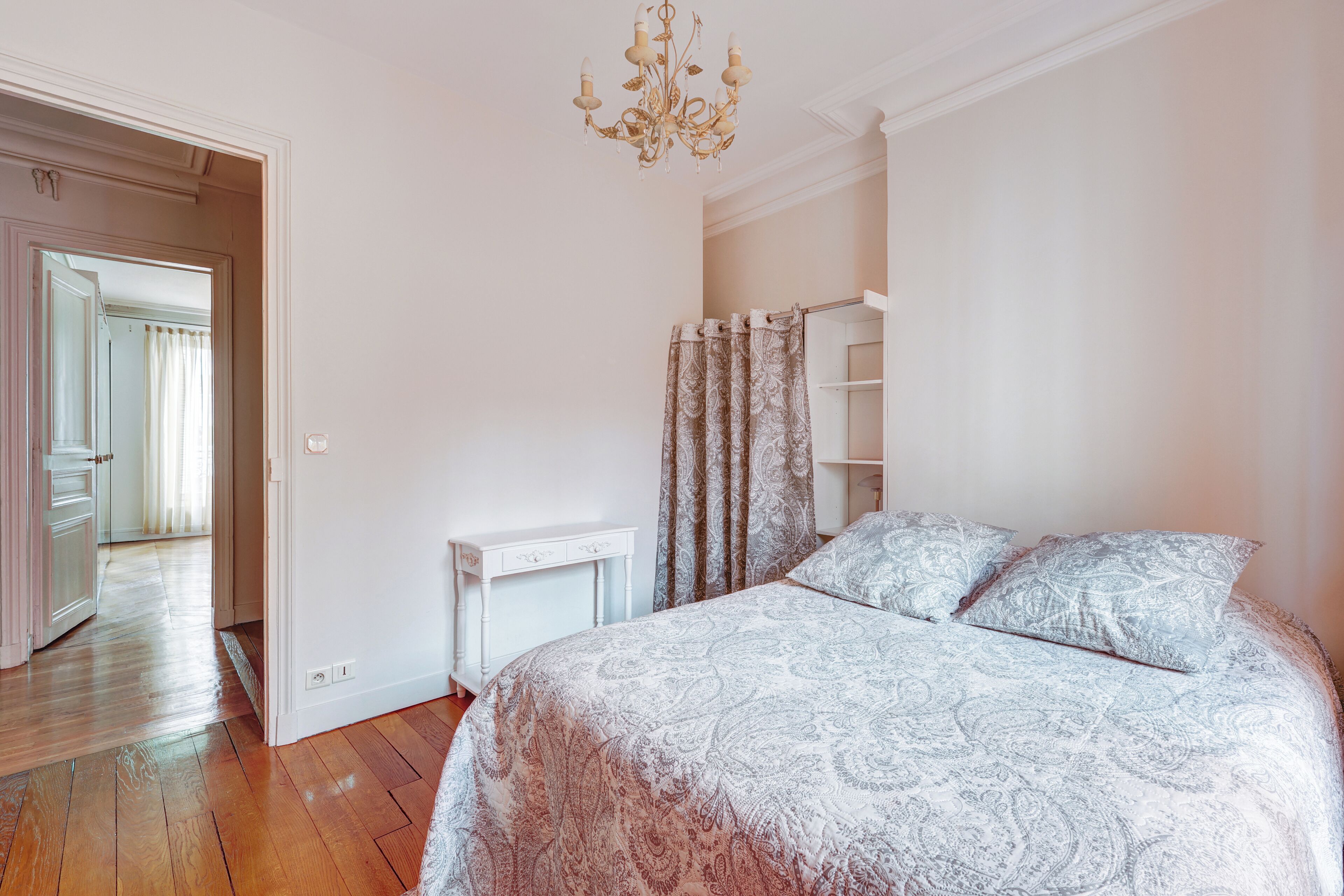 Een slaapkamer met een bed, een bureau en een kroonluchter.