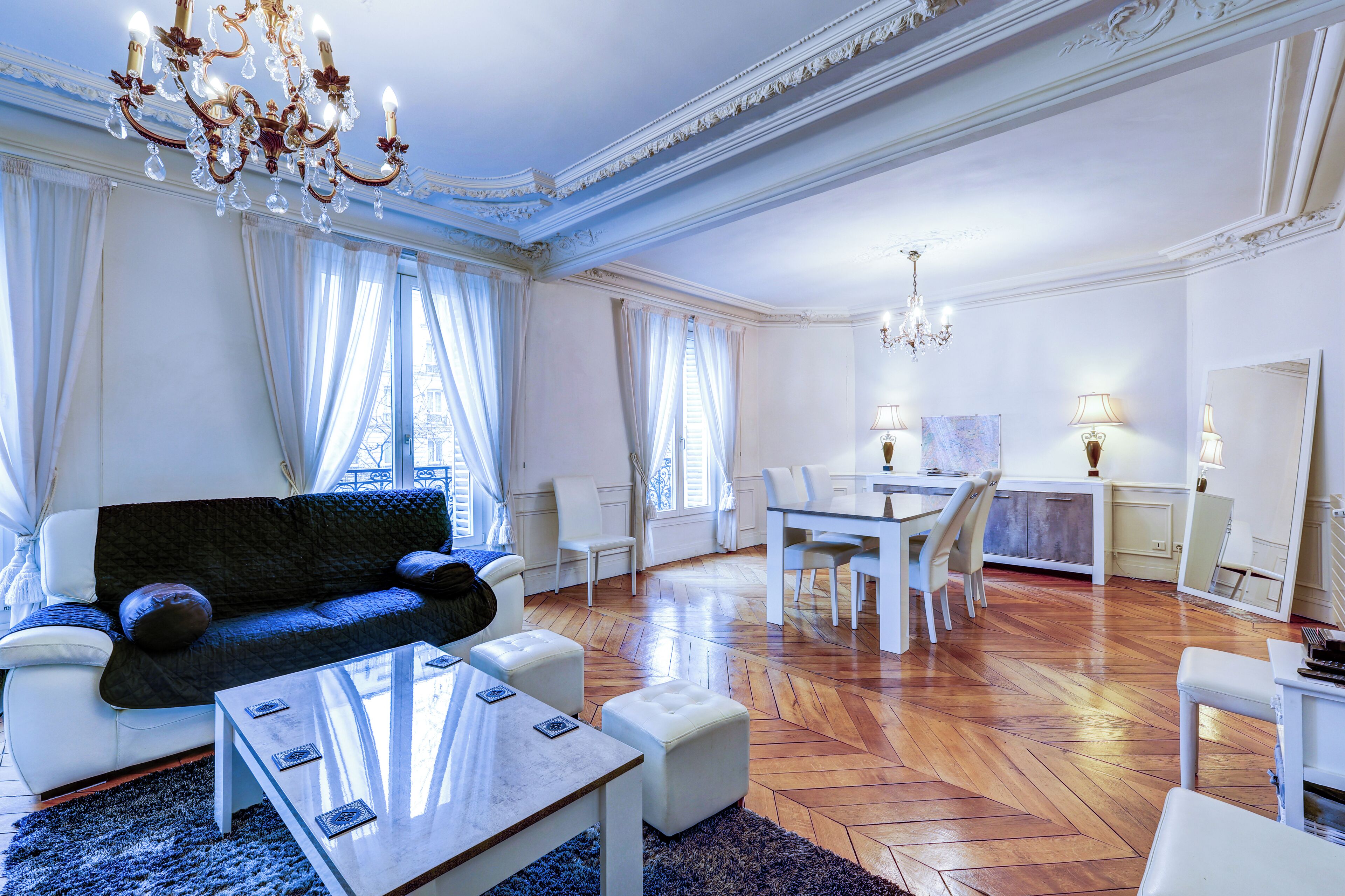 A spacious living room with a sofa, ottomans, a coffee table, and a dining area with chairs and a table.