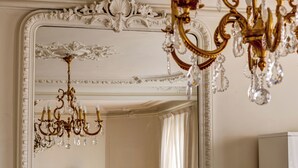 Ein Zimmer mit aufwendigen weißen und goldenen Kronleuchtern, einem großen Spiegel und einem weißen Schrank.