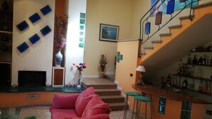 A living room with a red sofa, a glass coffee table, and a bar area with stools. - Extra privacy, Dog-friendly, Family-friendly, Unspoiled nature, VerdeMare Beggi (Casale marittimo)