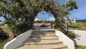 A stone staircase leading up to a white building, surrounded by lush greenery and flowering plants. - Alto Club, Alvor. Quiet, comfortable apartment in this acclaimed holiday resort (Alvor)
