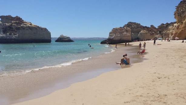 A beach with clear blue water, rocky formations, and people sunbathing. - Alto Club, Alvor. Quiet, comfortable apartment in this acclaimed holiday resort (Alvor)
