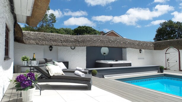 A private pool area with a lounge chair, a hot tub, and a small table with a bottle and glasses. - Luxury villa for 22 people with pool, jacuzzi, large garden and private pub! (Three Legged Cross)