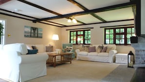 A cozy living room with two white sofas, a wooden coffee table, and a fireplace. - Luxury villa for 22 people with pool, jacuzzi, large garden and private pub! (Three Legged Cross)