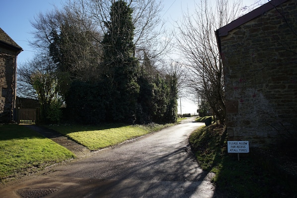 A narrow rural road with a sign on the right.