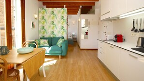 A modern kitchen with white cabinets, a wooden dining table, and a green sofa.