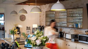 A modern kitchen with pendant lighting, a clock, and a glass display of wine glasses.
