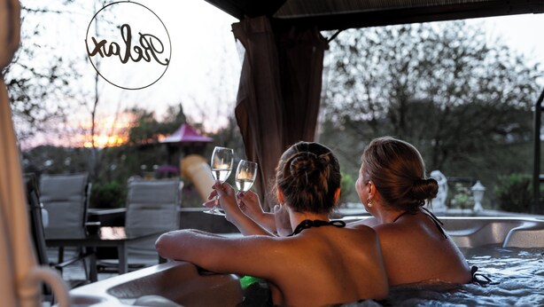 Two people in a hot tub with a sunset in the background.