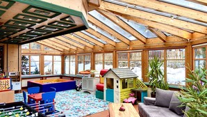 A spacious indoor play area with a foosball table, playhouse, and various toys.