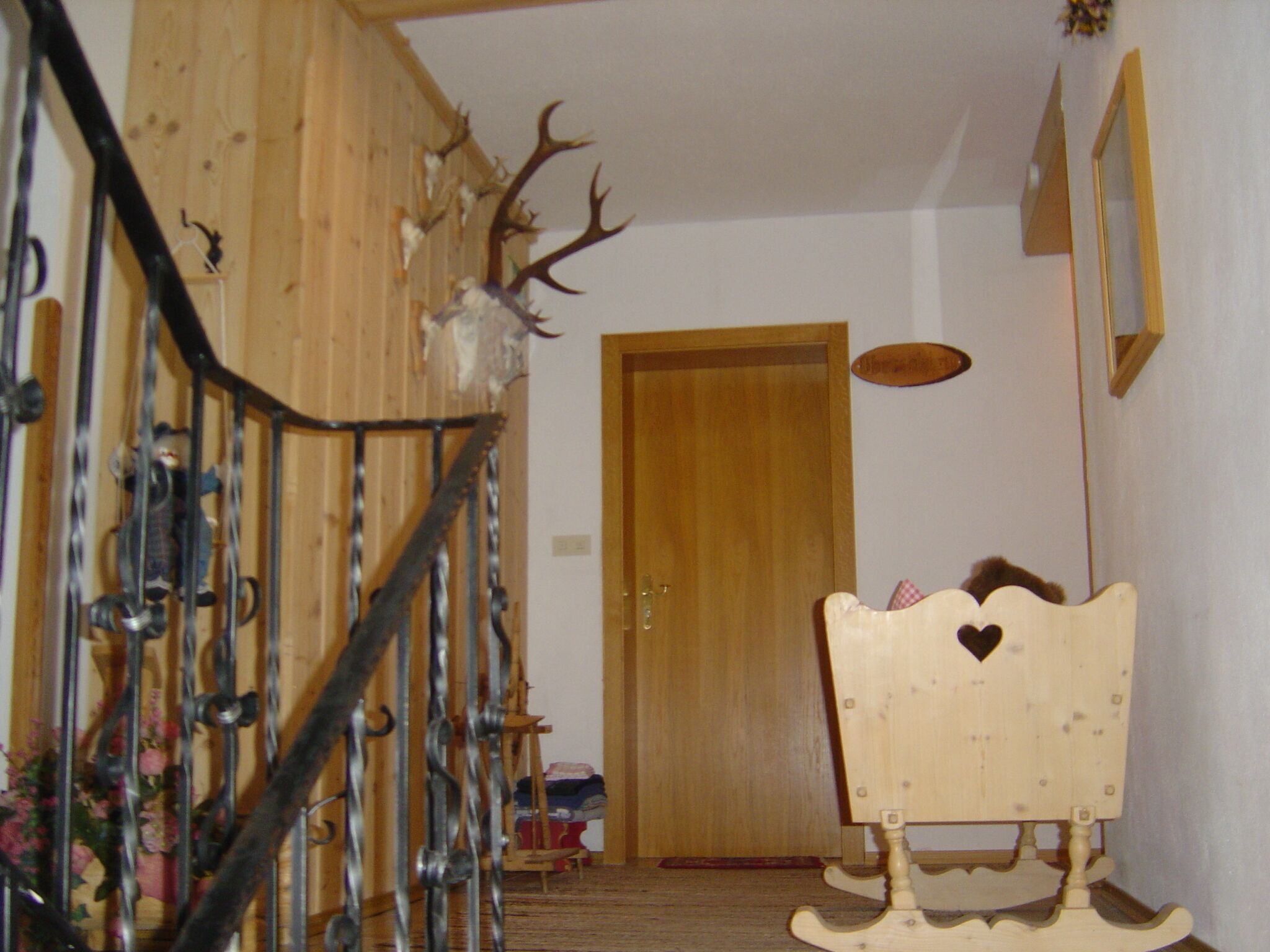A wooden staircase with metal railings, a wooden door at the top, and a rocking chair in the foreground.