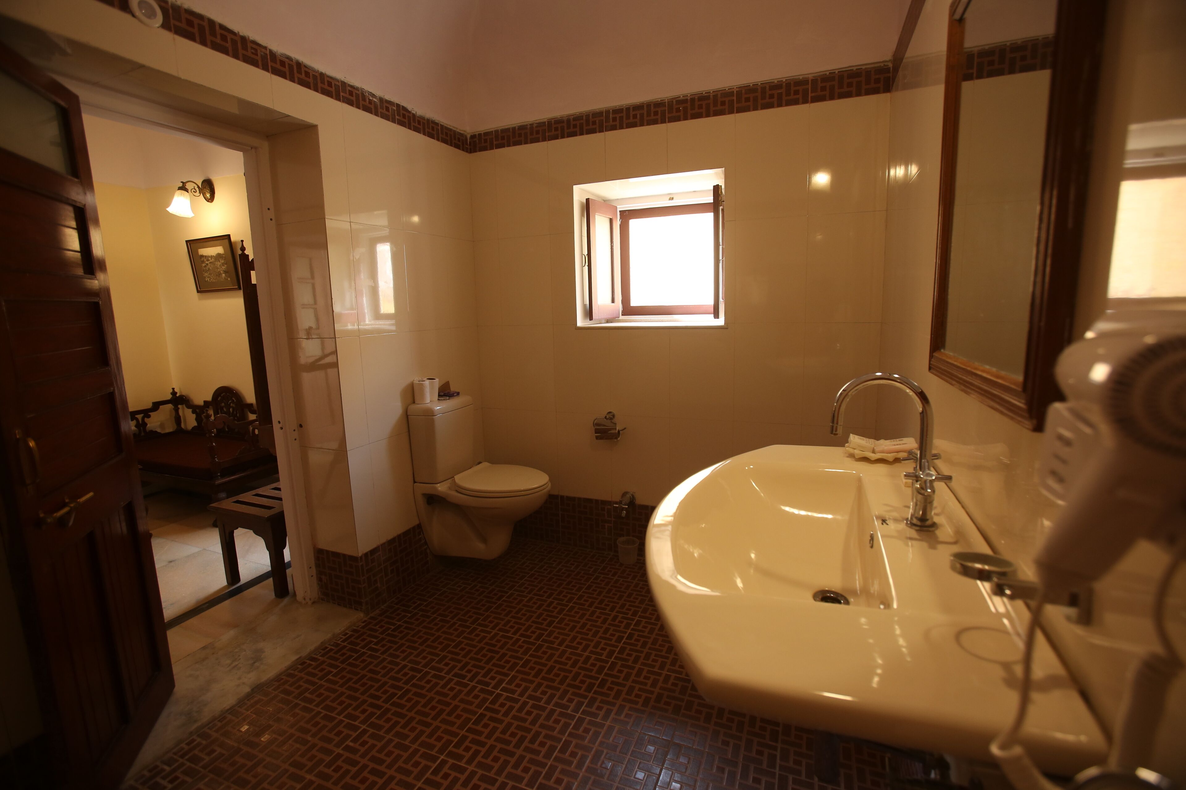A bathroom with a toilet, sink, and a window.