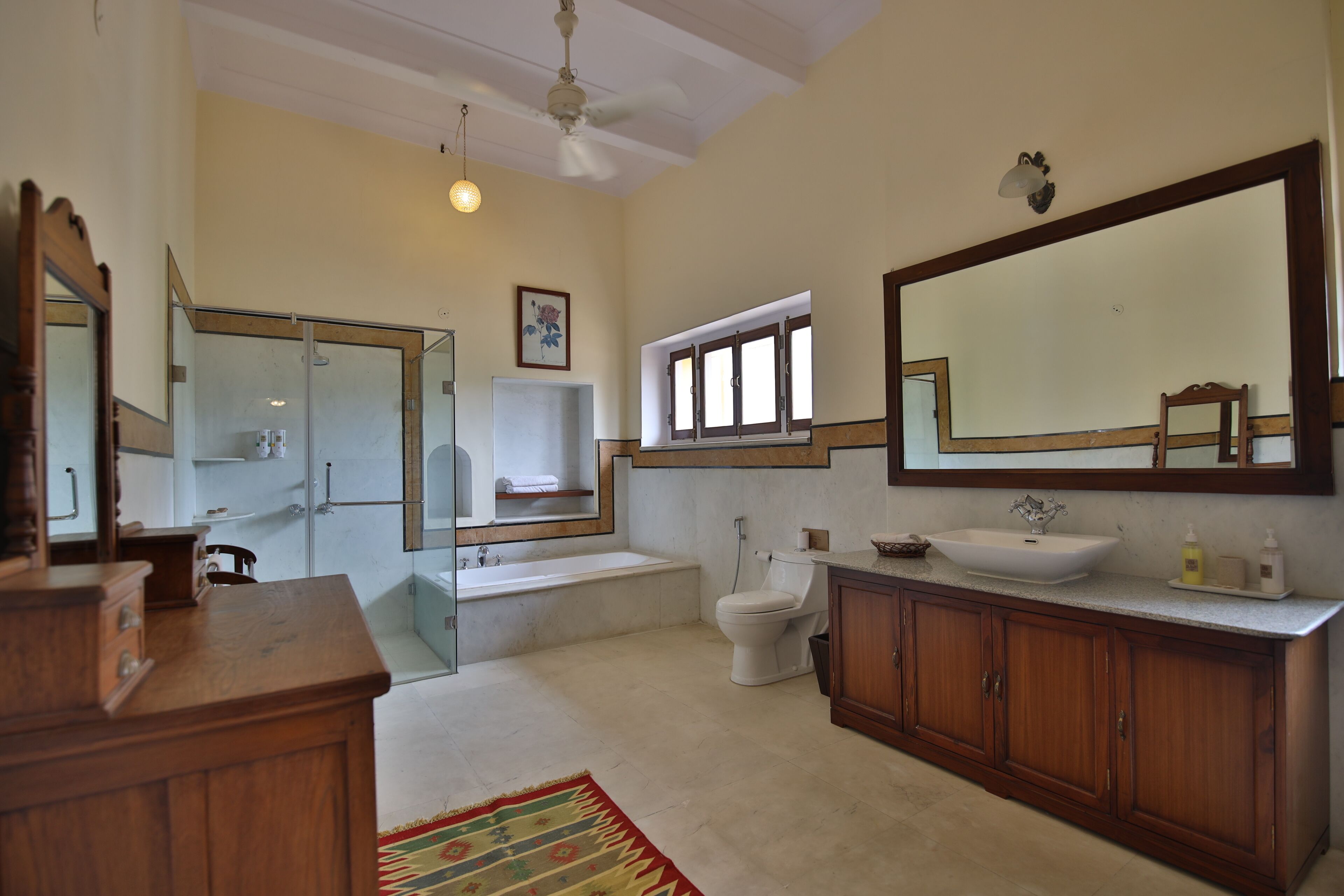 A spacious bathroom with a large mirror, a bathtub, a toilet, and a sink.