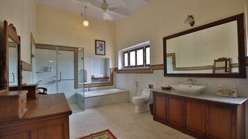 A spacious bathroom with a large mirror, a bathtub, a toilet, and a sink.