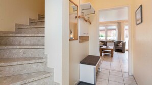 Una escala que condueix a una zona d'estar amb una banca, un penjador i una porta a un altre espai.