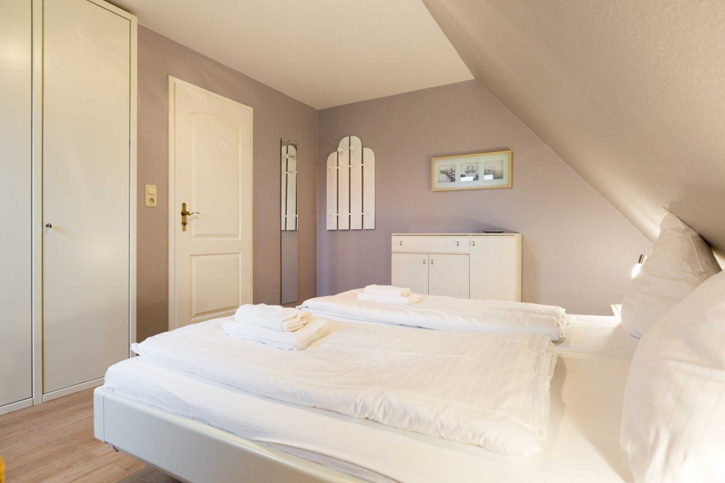 Une chambre à coucher avec un lit, une armoire et un petit meuble.