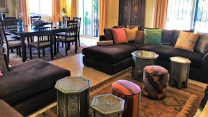Un salon spacieux avec un canapé aux couleurs sombres, une table à manger avec des chaises et un grand meuble décoratif.