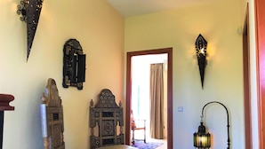 Une pièce avec une chaise en bois de style traditionnel, un lit à motifs et des appliques murales décoratives.