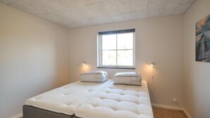 Une petite chambre avec un lit simple, une fenêtre, deux lampes de chevet et un tableau au mur.