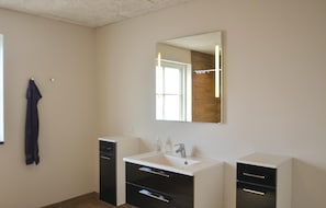 Ein Badezimmer mit einem weißen Waschbecken, einem Spiegel und einem Handtuch an der Wand.