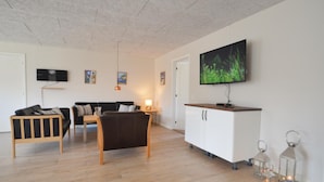 Un salon moderne comprenant un canapé, une table à manger, un téléviseur et un meuble.