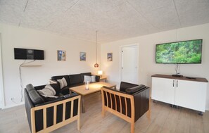 A modern living room with a sofa, a wooden coffee table, a TV, and a cabinet.