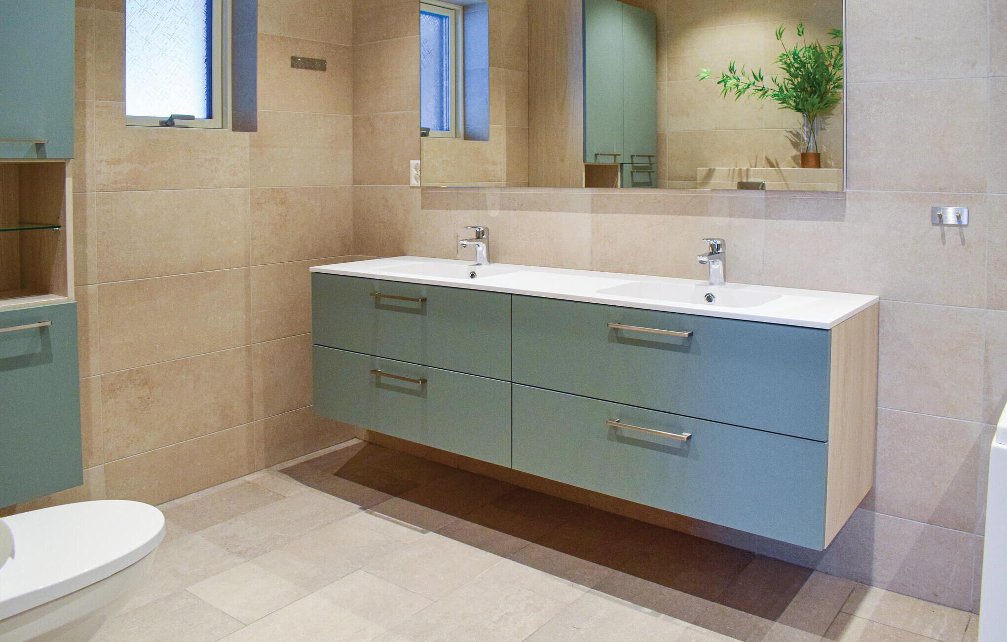 Une salle de bain moderne avec un grand meuble-lavabo, deux vasques et un miroir au-dessus du meuble-lavabo.
