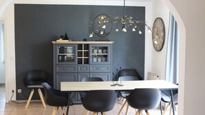 Un comedor con una mesa larga, seis sillas negras, un aparador con puertas de cristal y una lámpara decorativa.
