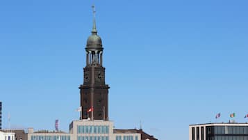 Ein historisches Gebäude mit einem Uhrturm, modernen Glasfenstern und Flaggen.