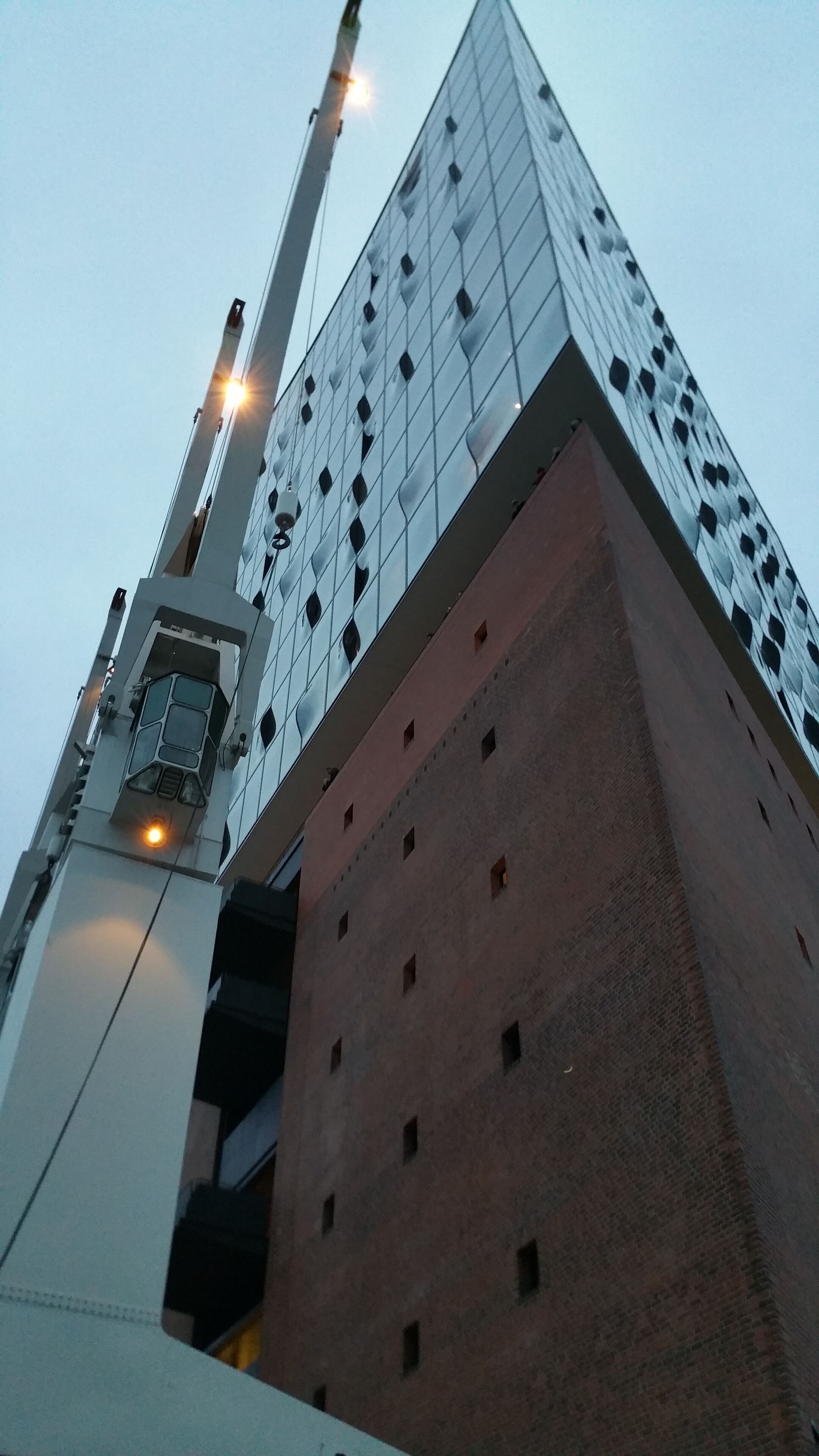 Een modern gebouw met een glazen gevel en een kraan.