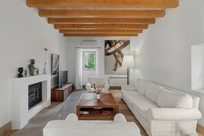 Una sala de estar moderna con chimenea, sofás blancos, una mesa de centro y un televisor.