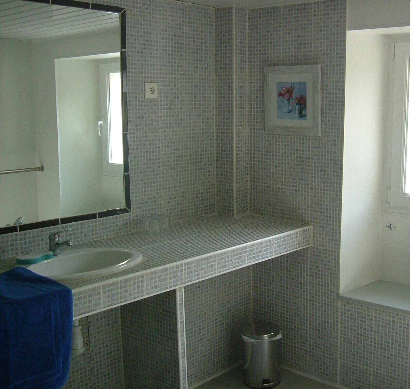 A bathroom with a sink, mirror, and tiled walls.