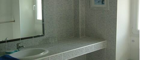 A bathroom with a sink, mirror, and tiled walls.