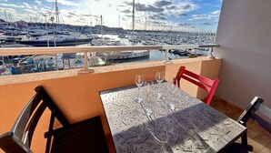 A balcony with a table set for four, overlooking a marina with numerous boats. - 2-Bedroom Apt Cabin, Parking, Pets Allowed - Cap d'Agde (Cap d'Agde)
