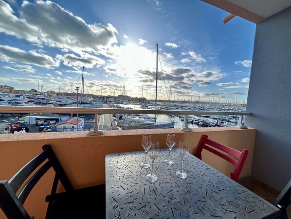 A balcony with a table and chairs overlooking a marina with numerous boats.