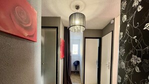 A hallway with a patterned floor, a chandelier, and a door with a red rose decoration. - 2-Bedroom Apt Cabin, Parking, Pets Allowed - Cap d'Agde (Cap d'Agde)