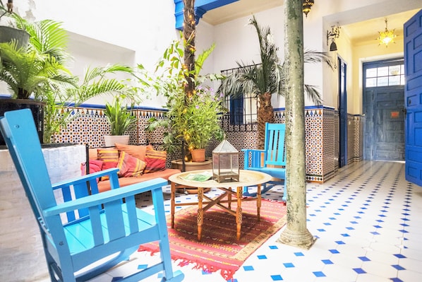A courtyard with blue furniture, a patterned floor, and potted plants.