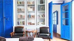 A room with a large bed, two black leather chairs, a small round table, and a bookshelf filled with books. - Large house, ideal private heated pool for family vacation (Vélez-Málaga)
