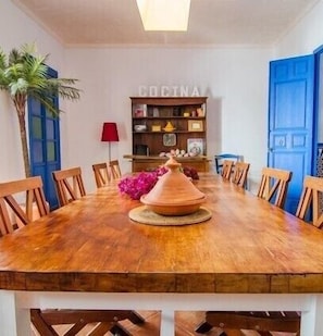 A dining area with a wooden table, chairs, a kitchen sign, and a blue door.
