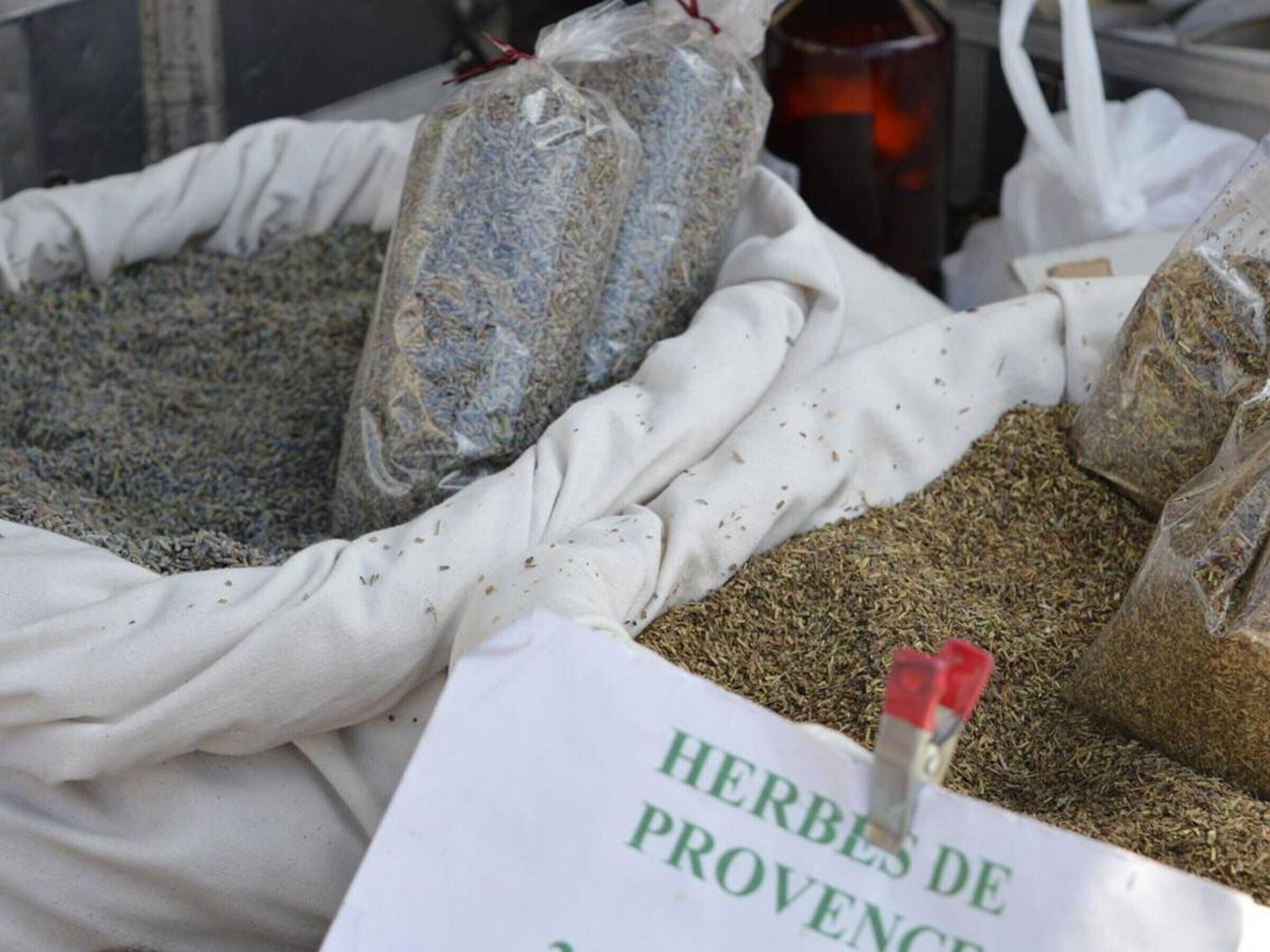 Bags of dried herbs labeled "HERBES DE PROVENCE" at a market stall.