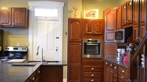 A kitchen with wooden cabinets, a stainless steel oven, a microwave, and a sink. - DOWNTOWN INDY HOME IN HISTORIC LOCKERBIE SQUARE  - 7 BLOCKS FROM CITY CENTER! (Indianapolis)