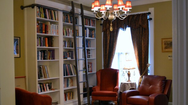 A room with a bookshelf, two leather chairs, a ladder, and a chandelier. - DOWNTOWN INDY HOME IN HISTORIC LOCKERBIE SQUARE  - 7 BLOCKS FROM CITY CENTER! (Indianapolis)