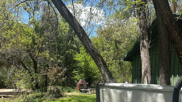 A hot tub with a control panel, surrounded by trees and a green building in the background. - Red rock canyon views! Private. Everything you need. Artist touches abound (Sedona)