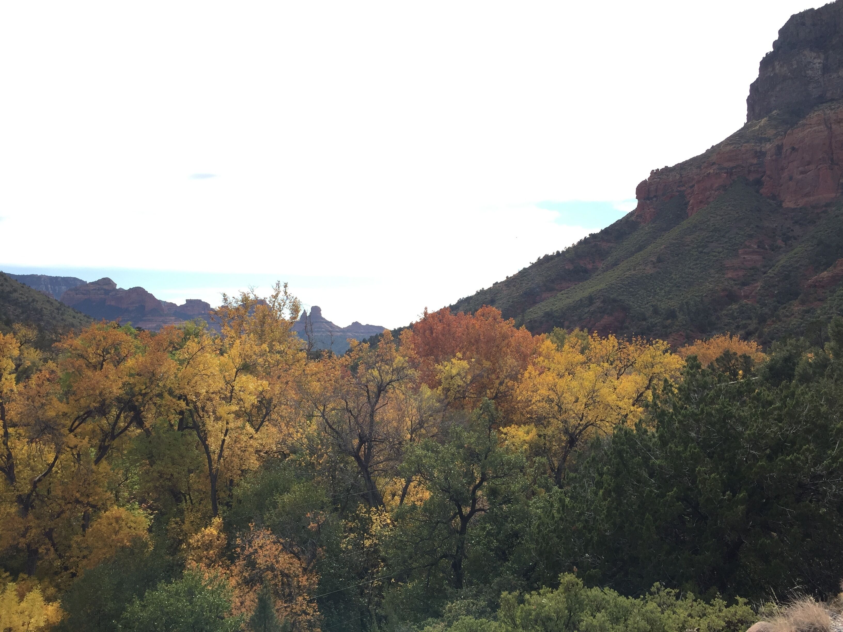A mountainous landscape with autumn-colored trees and rocky cliffs.