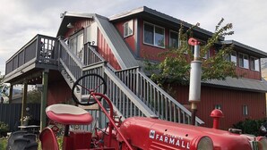 A red McCormick Farmall tractor parked in front of a red building with a staircase leading to a balcony.