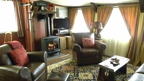 A cozy living room with leather sofas, a fireplace, a television, and a patterned rug.