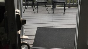 A deck with two chairs and a table, overlooking a hilly landscape.