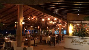 An indoor restaurant with wooden beams, hanging lights, and tables set for dining.