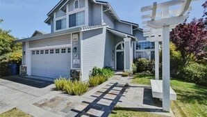 A two-story house with a garage, a front porch, and a small garden area. - Serenity at Natural Bridges  - 5 min Walk to Beach (Santa Cruz)