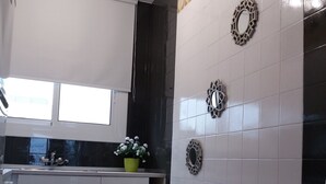 Une cuisine moderne avec des meubles blancs, une fenêtre et des carreaux décoratifs sur les murs.