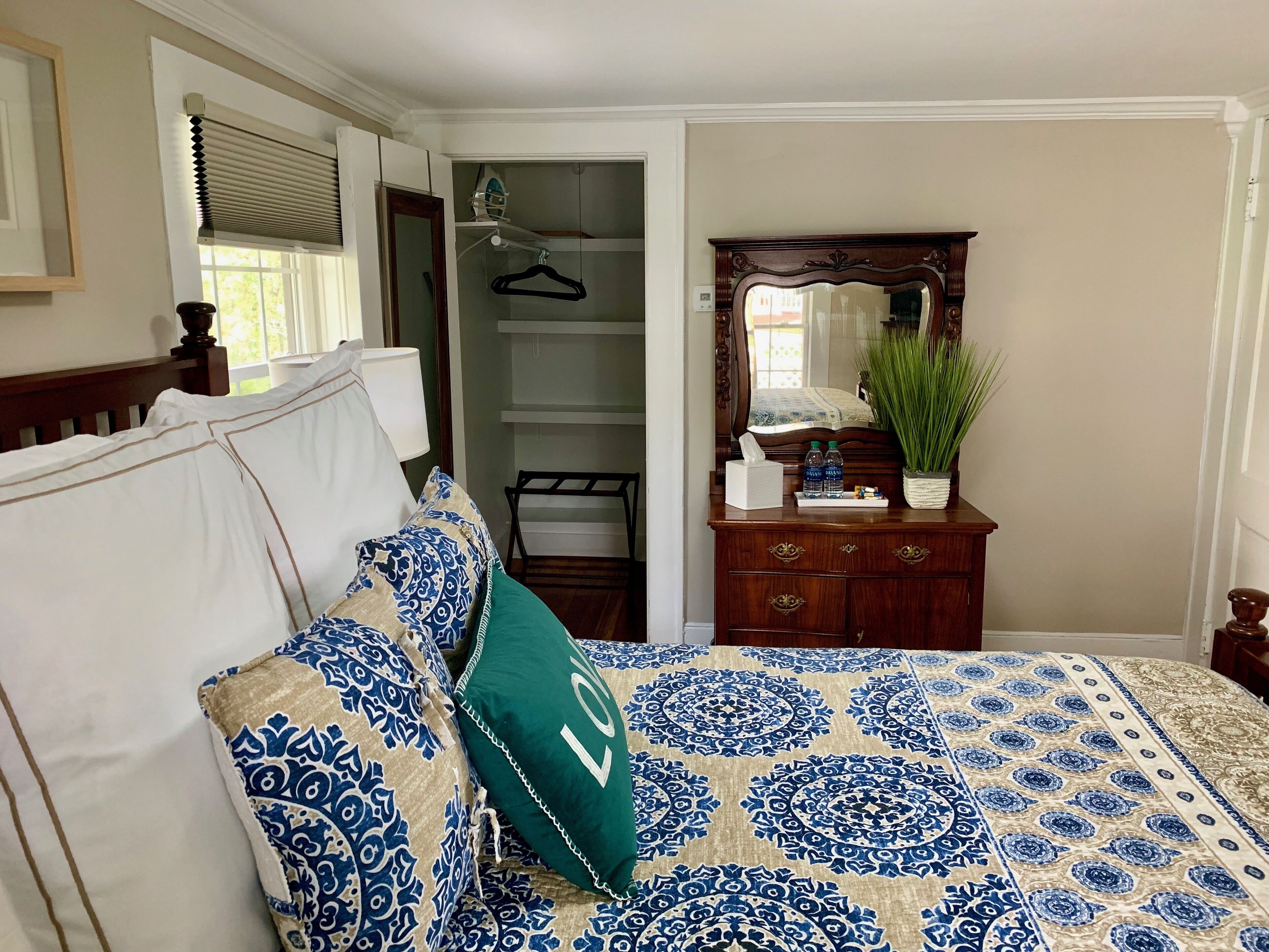 Une chambre à coucher avec un lit, une commode, un miroir et un placard.